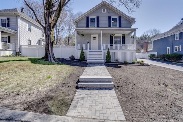 american foursquare style home with a front yard, a porch, and fence