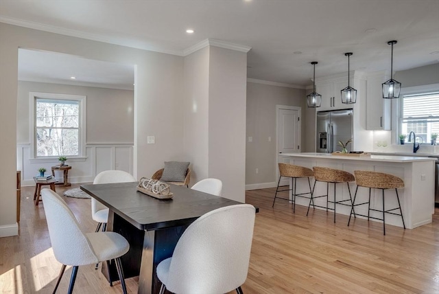 dining area with ornamental molding, light wood finished floors, wainscoting, and recessed lighting