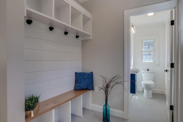 mudroom with light tile patterned floors, baseboards, and crown molding
