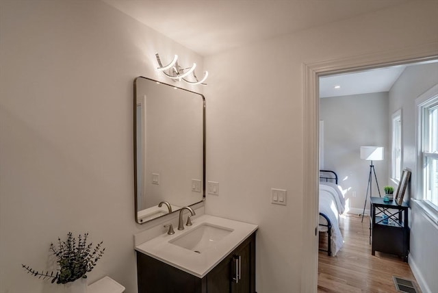 bathroom featuring wood finished floors, vanity, baseboards, and visible vents