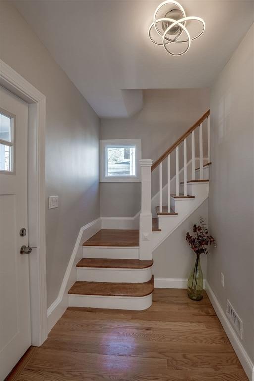 staircase featuring visible vents, baseboards, and wood finished floors