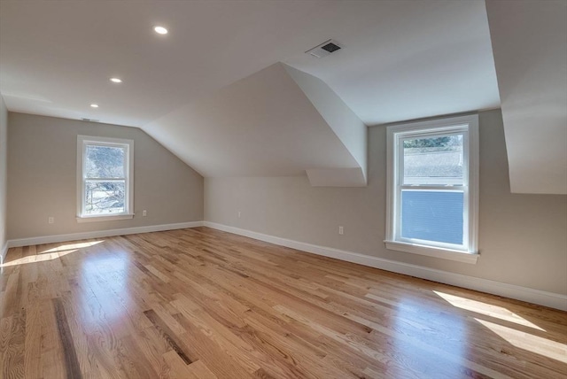 additional living space featuring light wood-type flooring, visible vents, baseboards, and vaulted ceiling