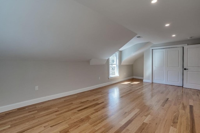 additional living space with light wood-style floors, vaulted ceiling, visible vents, recessed lighting, and baseboards