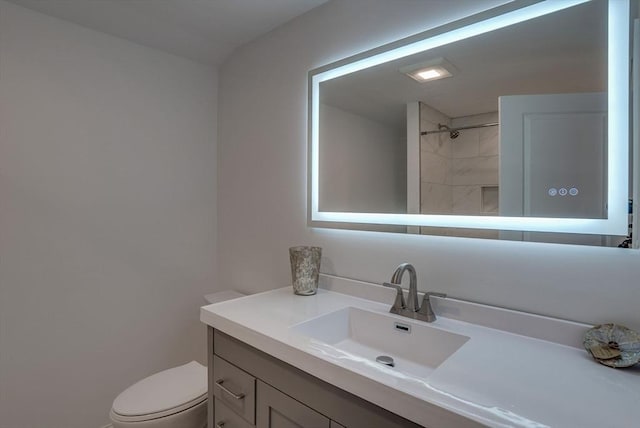 bathroom featuring toilet, vanity, and walk in shower