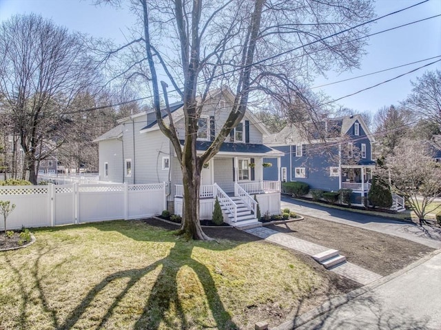 view of front of house featuring a porch, fence, and a front lawn
