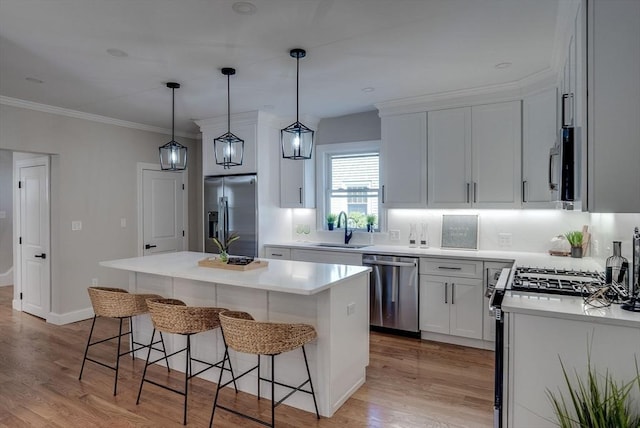 kitchen featuring a center island, a sink, appliances with stainless steel finishes, white cabinetry, and a breakfast bar area