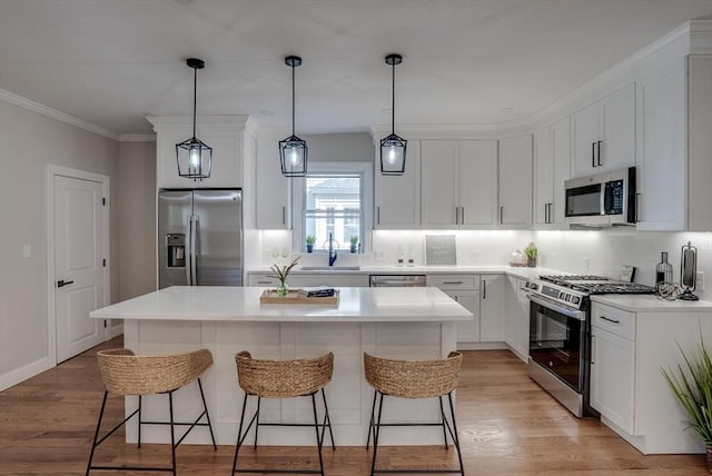 kitchen featuring a kitchen breakfast bar, a kitchen island, white cabinets, stainless steel appliances, and a sink