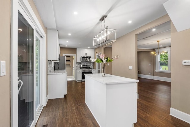 186 Chapel St, Abington, MA 02351 - kitchen featuring appliances with stainless steel finishes, a kitchen island, white cabinetry, dark wood finished floors, and backsplash