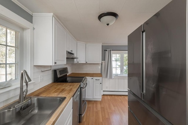 kitchen with stainless steel appliances, butcher block counters, white cabinets, a sink, and under cabinet range hood