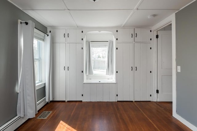 unfurnished bedroom featuring dark wood-type flooring, two closets, and visible vents