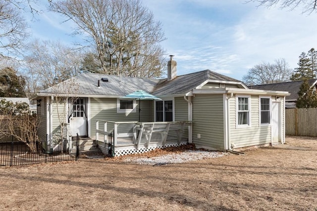 rear view of house featuring fence, a chimney, and a wooden deck