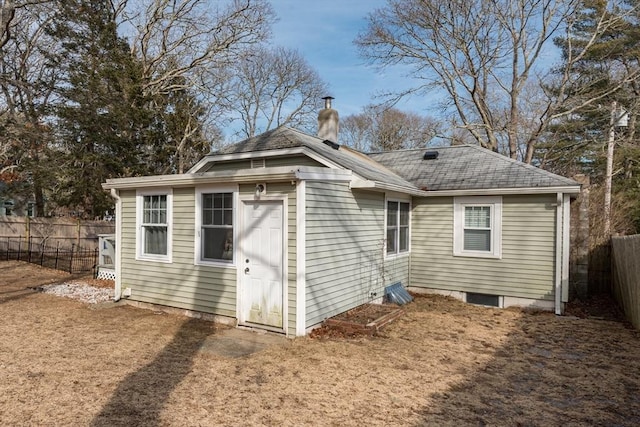 exterior space featuring a shingled roof, fence, and a chimney