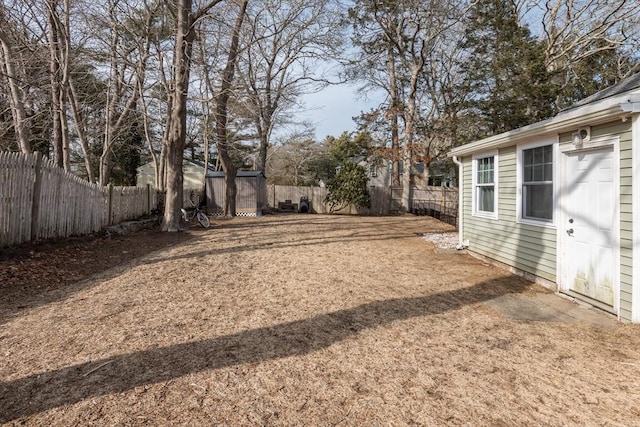 view of yard with a fenced backyard, an outdoor structure, and a storage unit