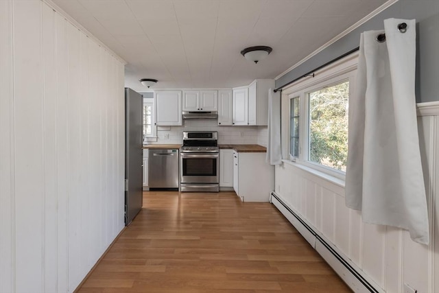 kitchen with appliances with stainless steel finishes, light wood-style floors, a baseboard heating unit, white cabinetry, and under cabinet range hood