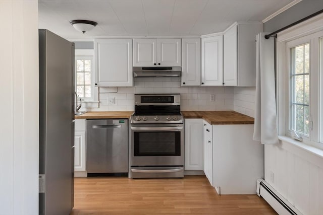 kitchen with a baseboard radiator, appliances with stainless steel finishes, under cabinet range hood, white cabinetry, and wooden counters