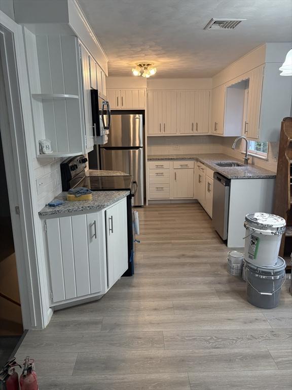 945 Shoemaker Ln, Agawam, MA 01030 - kitchen featuring appliances with stainless steel finishes, light wood-type flooring, light stone counters, and open shelves