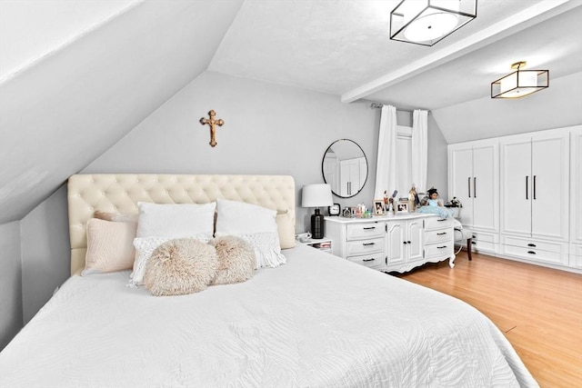 bedroom with light wood finished floors and vaulted ceiling