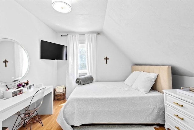 bedroom featuring light wood-type flooring and vaulted ceiling