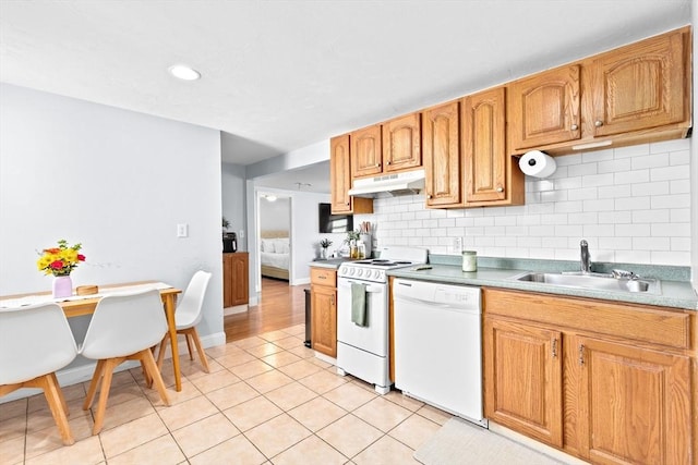 kitchen featuring a sink, under cabinet range hood, light tile patterned floors, backsplash, and white appliances