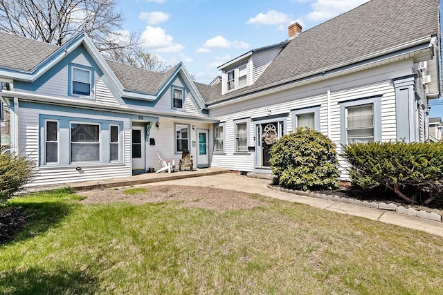 view of front facade featuring roof with shingles, a chimney, and a front yard