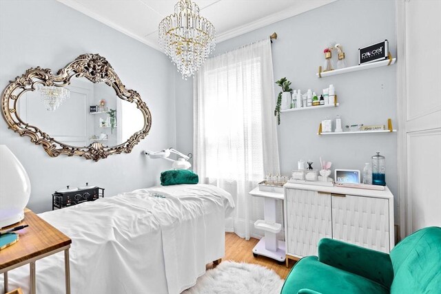 bedroom with crown molding, an inviting chandelier, radiator heating unit, and wood finished floors