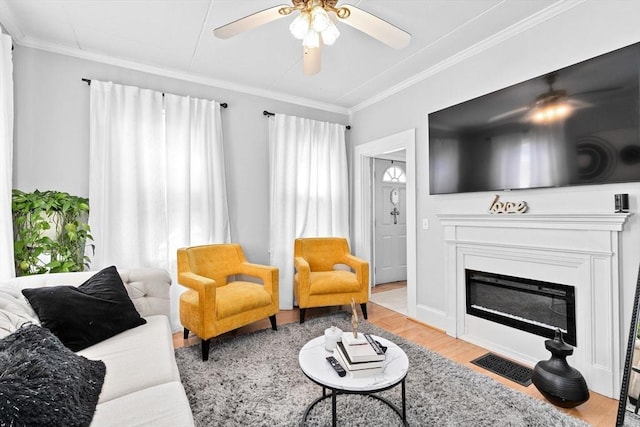 living room featuring ornamental molding, ceiling fan, wood finished floors, and visible vents