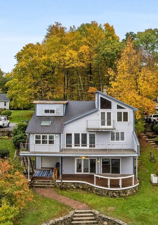 rear view of house with a balcony and a lawn