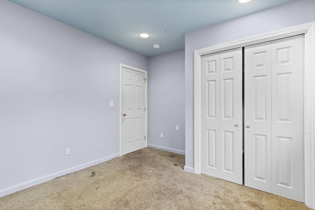 unfurnished bedroom with light colored carpet and a closet