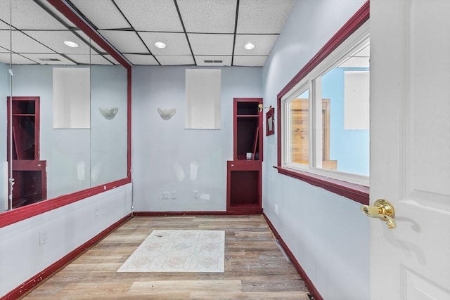 corridor featuring a drop ceiling and light hardwood / wood-style floors