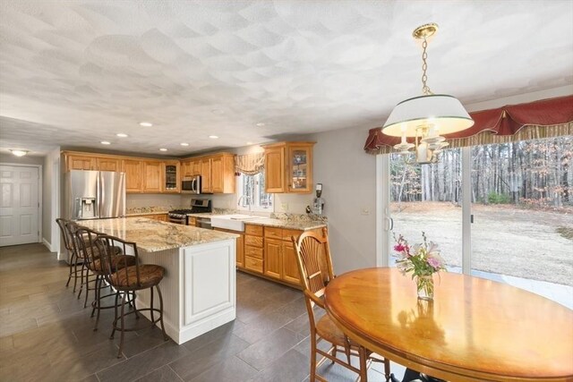 2 Spencer Way, Merrimac, MA 01860 - kitchen featuring a breakfast bar, light stone countertops, stainless steel appliances, glass insert cabinets, and a center island