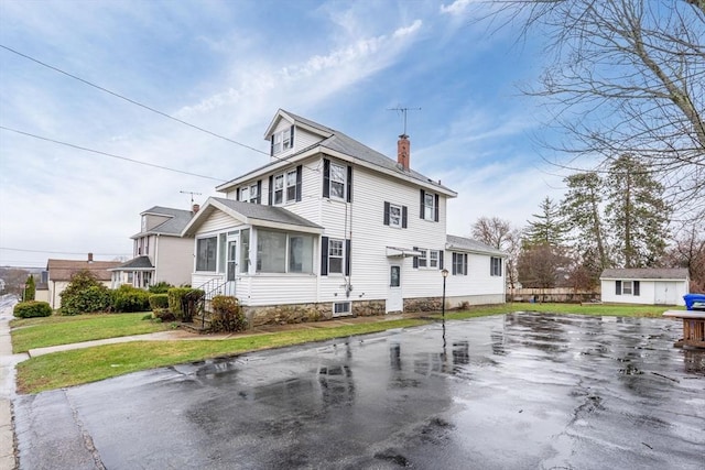 view of front of house with a chimney, a front yard, and a sunroom