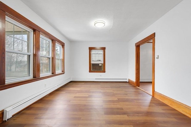 spare room featuring a baseboard radiator, baseboards, cooling unit, and wood finished floors