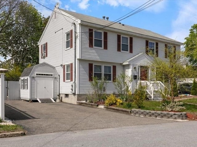 view of front facade with driveway, an outbuilding, a shed, and a garage