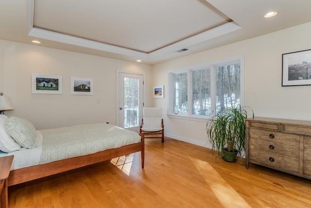 bedroom with light wood-type flooring and a raised ceiling