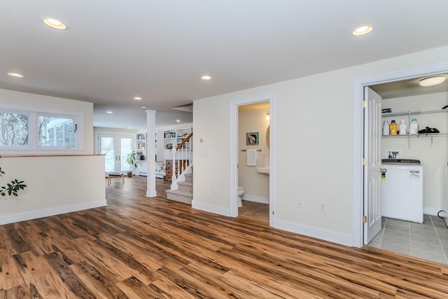 interior space with hardwood / wood-style flooring, decorative columns, washer / clothes dryer, and french doors