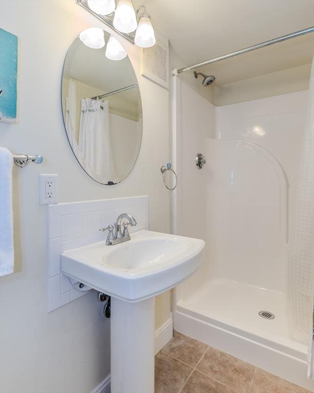 bathroom with a shower with shower curtain, tile patterned flooring, and a chandelier