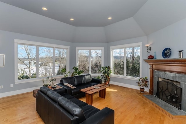 living room with light hardwood / wood-style flooring, vaulted ceiling, and a high end fireplace