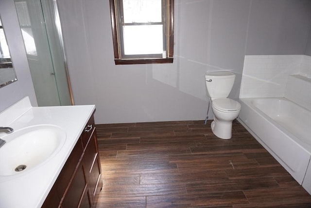 bathroom featuring a bathtub, toilet, wood finished floors, and vanity