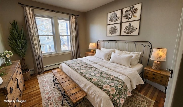 bedroom featuring light wood-type flooring and a baseboard heating unit