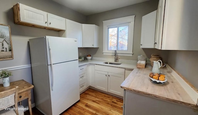 kitchen featuring white cabinets, sink, white refrigerator, and light hardwood / wood-style flooring