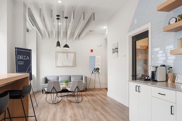 dining area with baseboards, light wood-style flooring, and vaulted ceiling