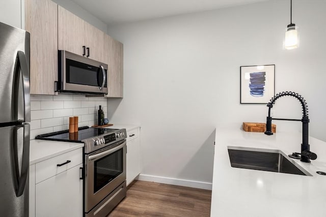 kitchen featuring decorative backsplash, dark wood-style floors, light countertops, a sink, and stainless steel appliances