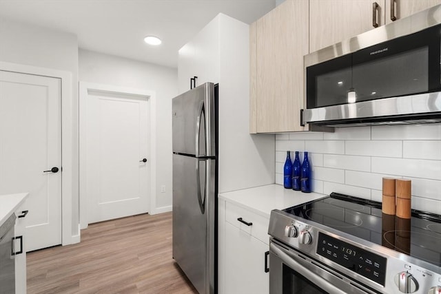 kitchen with backsplash, appliances with stainless steel finishes, light countertops, recessed lighting, and light wood-style flooring