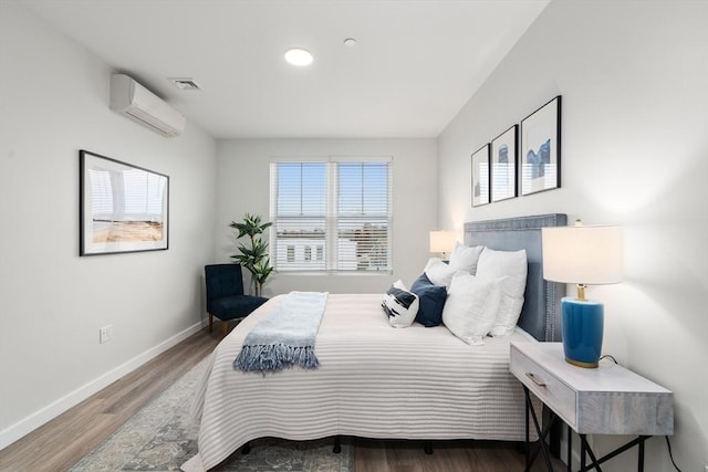 bedroom with baseboards, a wall mounted AC, and wood finished floors