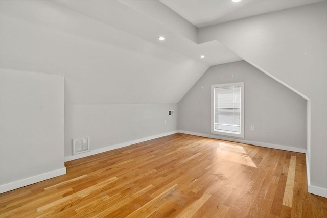 additional living space with light wood-type flooring, visible vents, lofted ceiling, and baseboards