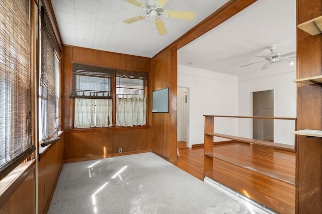 unfurnished room featuring ceiling fan, baseboards, and wood walls