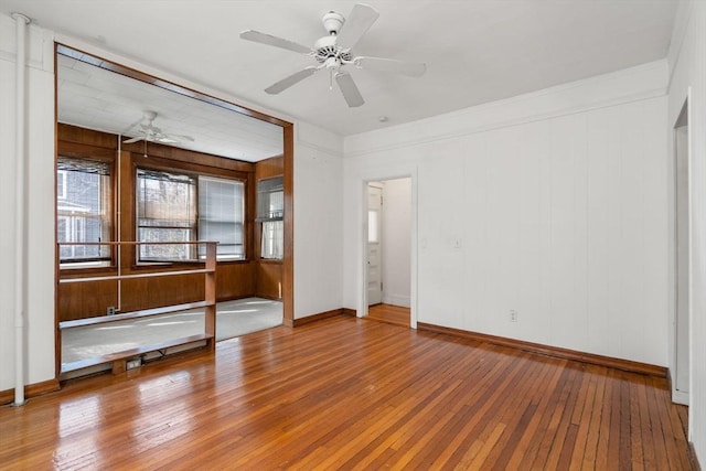 spare room featuring baseboards, a ceiling fan, and hardwood / wood-style flooring