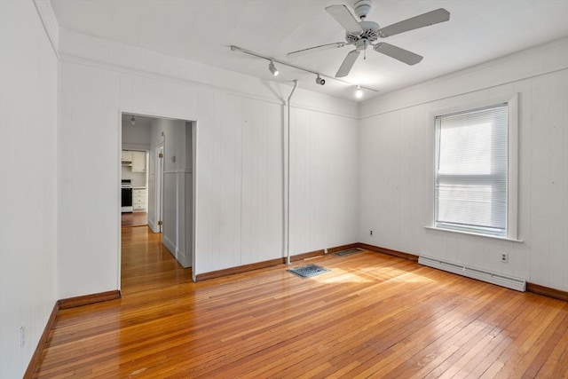 spare room with a baseboard radiator, visible vents, a ceiling fan, and light wood finished floors