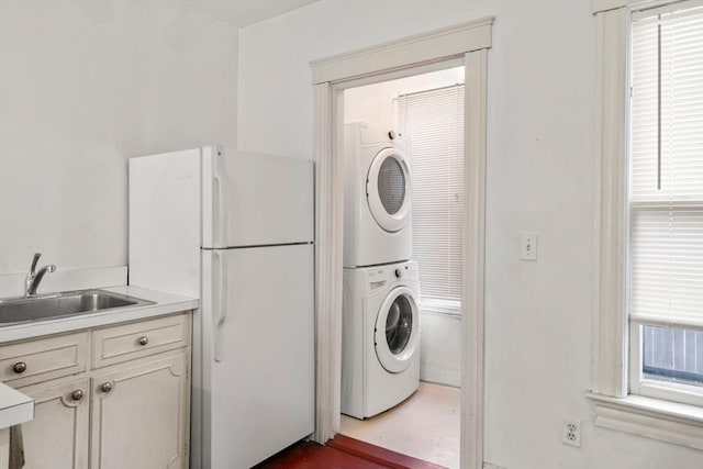 laundry room with laundry area, stacked washer / dryer, a healthy amount of sunlight, and a sink