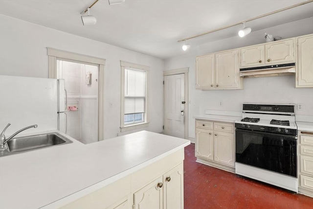 kitchen with gas stove, freestanding refrigerator, a sink, light countertops, and under cabinet range hood